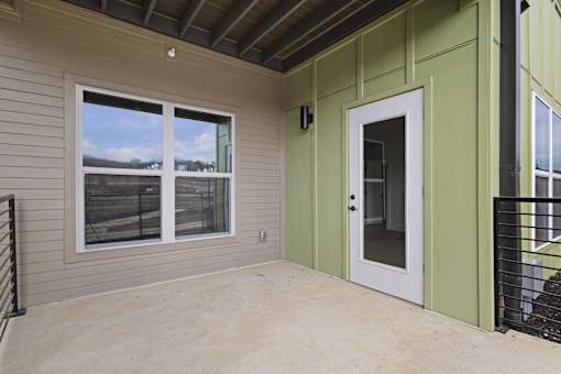 A balcony with a white door and a window overlooking a fence.