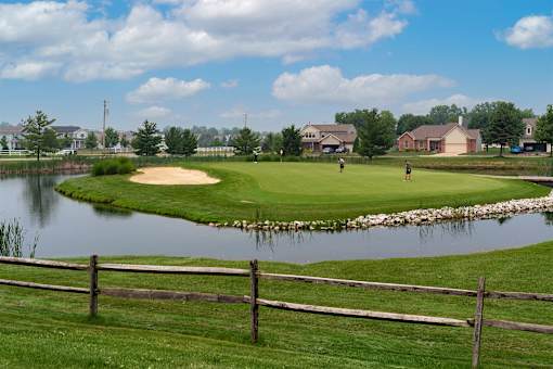 A golf course with a pond and a fence.