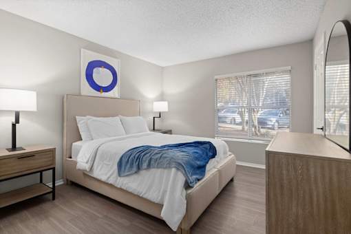 A bedroom with a bed, nightstand, and lamp.