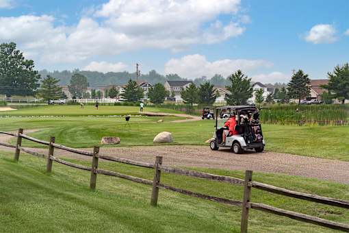 A golf cart is driving down a path in a grassy area.