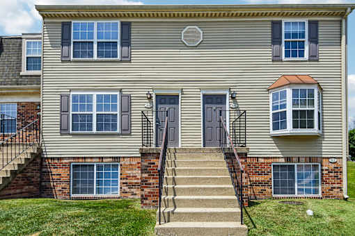 A two-story house with a grey facade and a brick base.