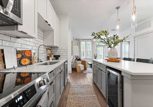 A modern kitchen with a large island and a vase of greenery on top.