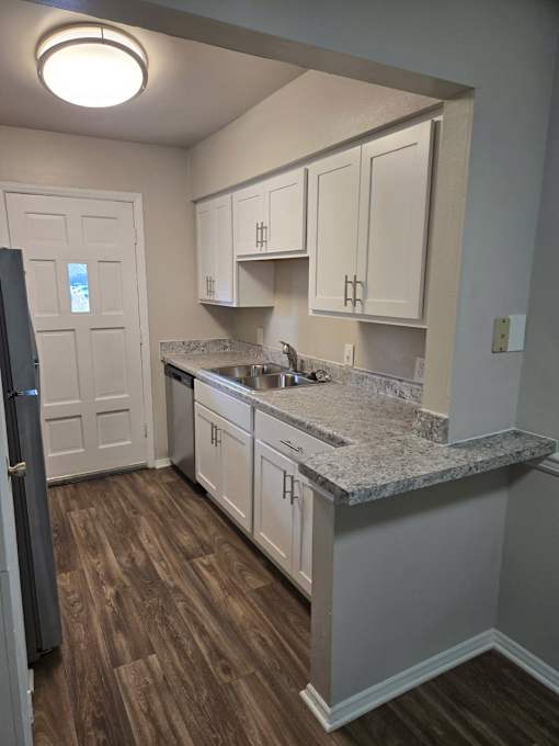 A kitchen with a granite countertop and white cabinets.