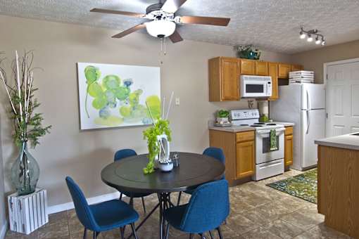 A kitchen with a table and chairs in the foreground and a painting on the wall.