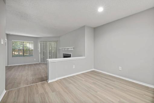 A spacious room with light grey walls and wooden flooring.