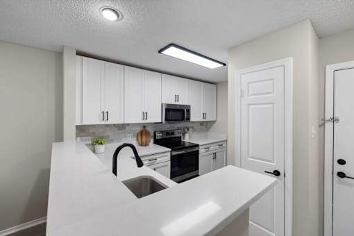 A kitchen with white cabinets and a white countertop.