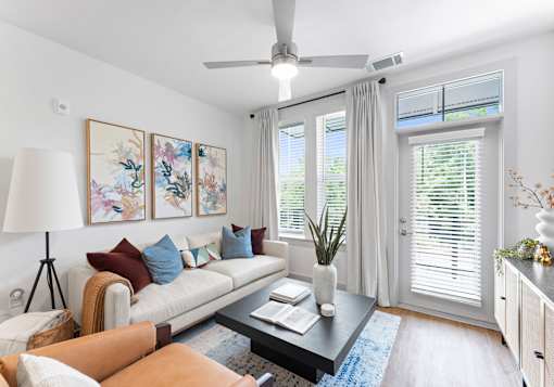 A living room with a white couch, a brown leather chair, a coffee table, and a painting on the wall.