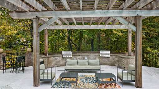 A wooden pergola with a couch and chairs underneath it.