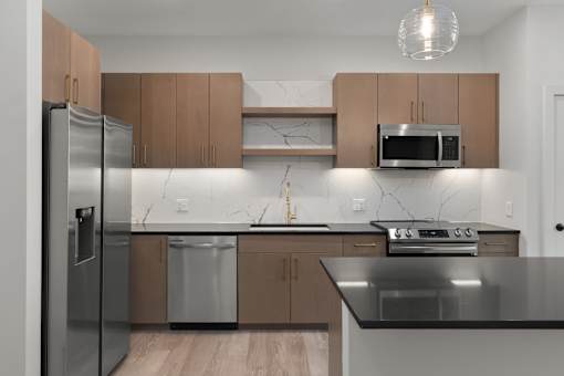 A modern kitchen with a stainless steel refrigerator, microwave, and oven.