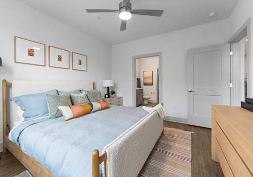 A bedroom with a bed, dresser, and ceiling fan.
