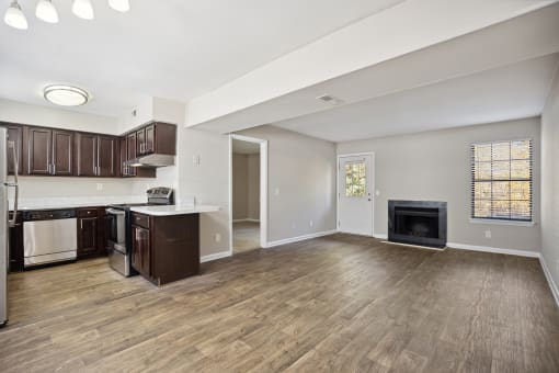 an empty living room with a kitchen and a fireplace