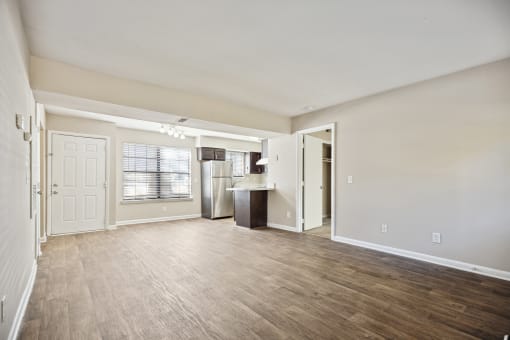 the living room and kitchen of an empty apartment with wood flooring