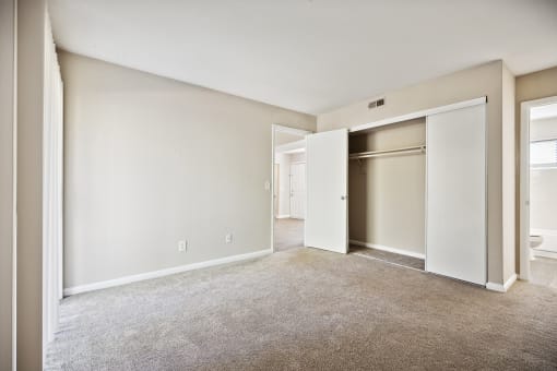 an empty living room with an open door to a closet