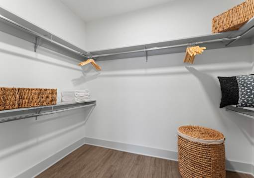 A room with a white wall and a shelf with baskets and towels.