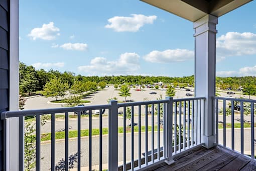 A view from a balcony overlooking a street with cars and trees.