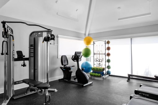a home gym with exercise equipment and a colorful ball on the ceiling