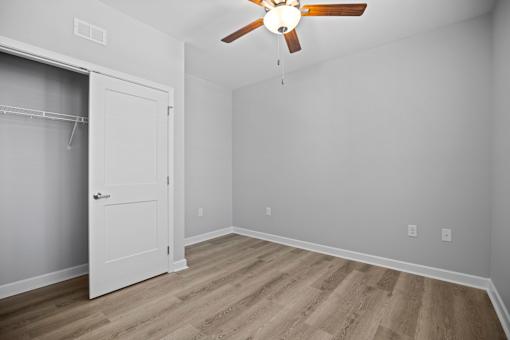 A room with a white door and a ceiling fan.