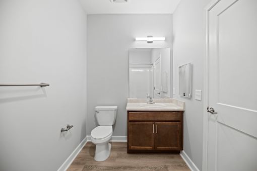 A white bathroom with a toilet, sink, and mirror.