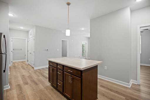 A kitchen with a white counter top and wooden floors.