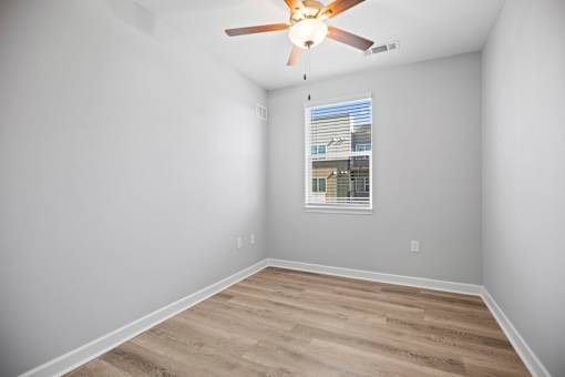 A room with a ceiling fan and a window with blinds.