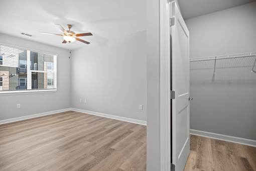 A room with a ceiling fan and wooden flooring.
