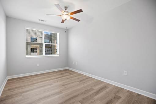 A room with a ceiling fan and a window with blinds.
