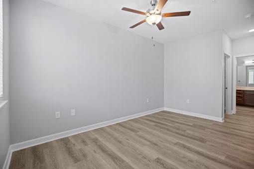 A room with a ceiling fan and wooden flooring.