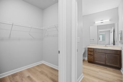A white bathroom with a wooden vanity and a white door.