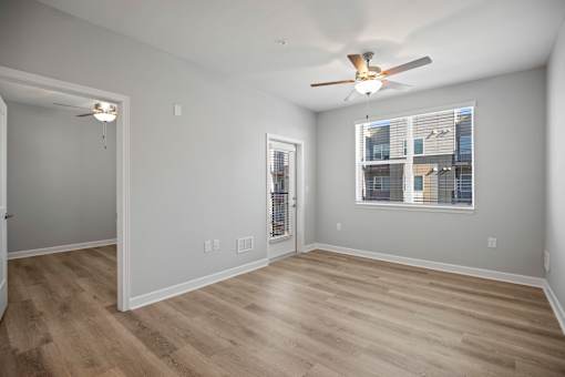 A room with a ceiling fan and a window with blinds.