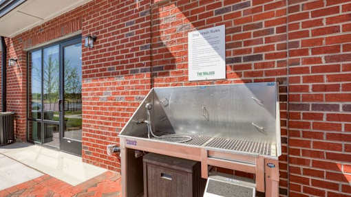 A metal grill is attached to a brick wall outside a building.