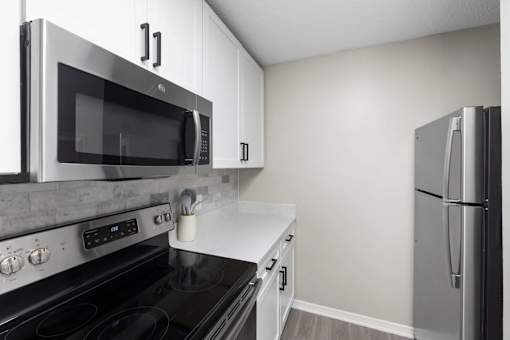 A modern kitchen with a black stove top oven and a black microwave above it.