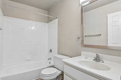A white bathroom with a toilet, sink, and bathtub.
