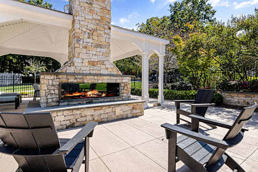 A patio with a fireplace and chairs.