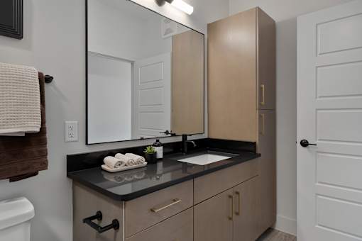 A bathroom with a sink, mirror, and cabinets.