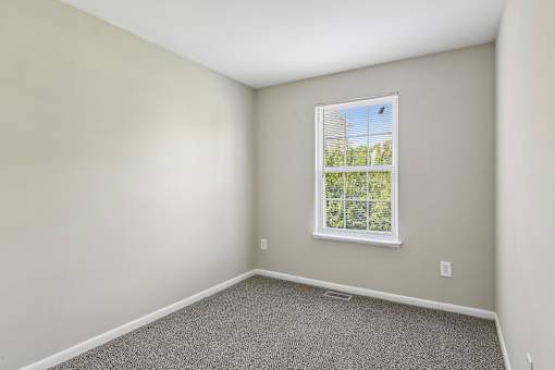 A room with a window and carpeted floor.