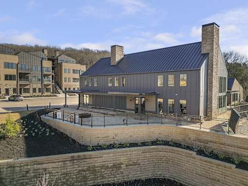 A modern building with a black roof and a stone wall in front.