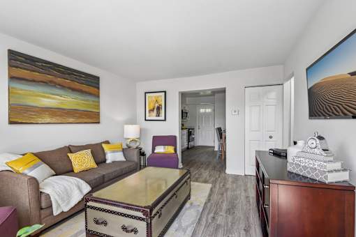 A living room with a brown couch and a painting on the wall.