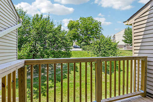 A wooden deck overlooks a grassy area with trees.
