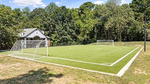 A soccer field with a goal post and a house in the background.