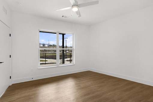 A room with a ceiling fan and a large window overlooking a parking lot.