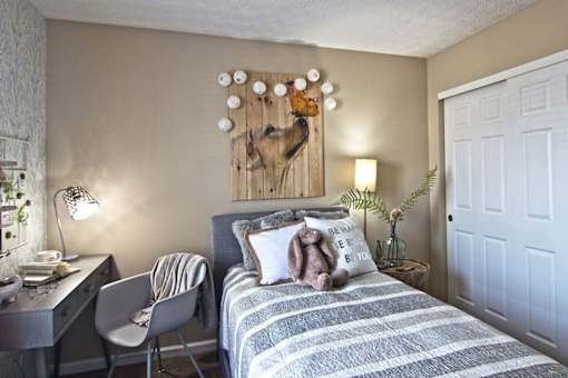 A bedroom with a bed, desk, chair, and a wall hanging.