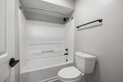 A white toilet sits next to a bathtub in a small bathroom.