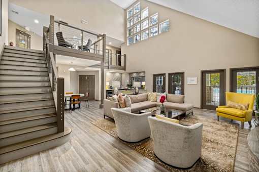 A living room with a staircase and a yellow chair.