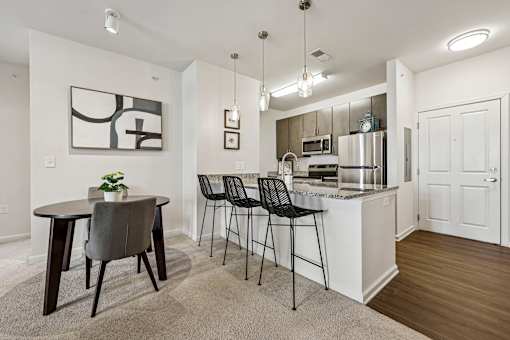 A kitchen with a table and chairs in front of it.