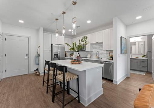 A modern kitchen with a white island and bar stools.