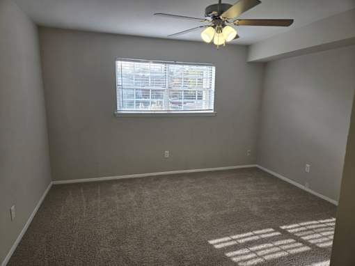 A room with a ceiling fan and a window with blinds.
