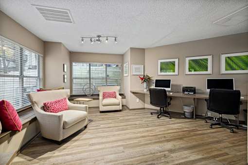 A room with a desk, chairs, and pictures on the wall.