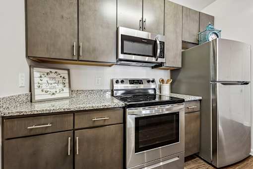 A kitchen with a stove, oven, refrigerator, and microwave.