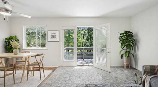 A room with a dining table and chairs, a potted plant, and a couch.