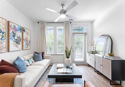 A living room with a white couch, a coffee table, and a ceiling fan.
